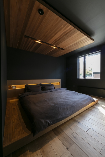 小上りに下がり天井の寝室。明るく照らしすぎない照明計画に、電子機器の充電からインテリアの置き場所まで、暮らし方に合わせて利用ができる
